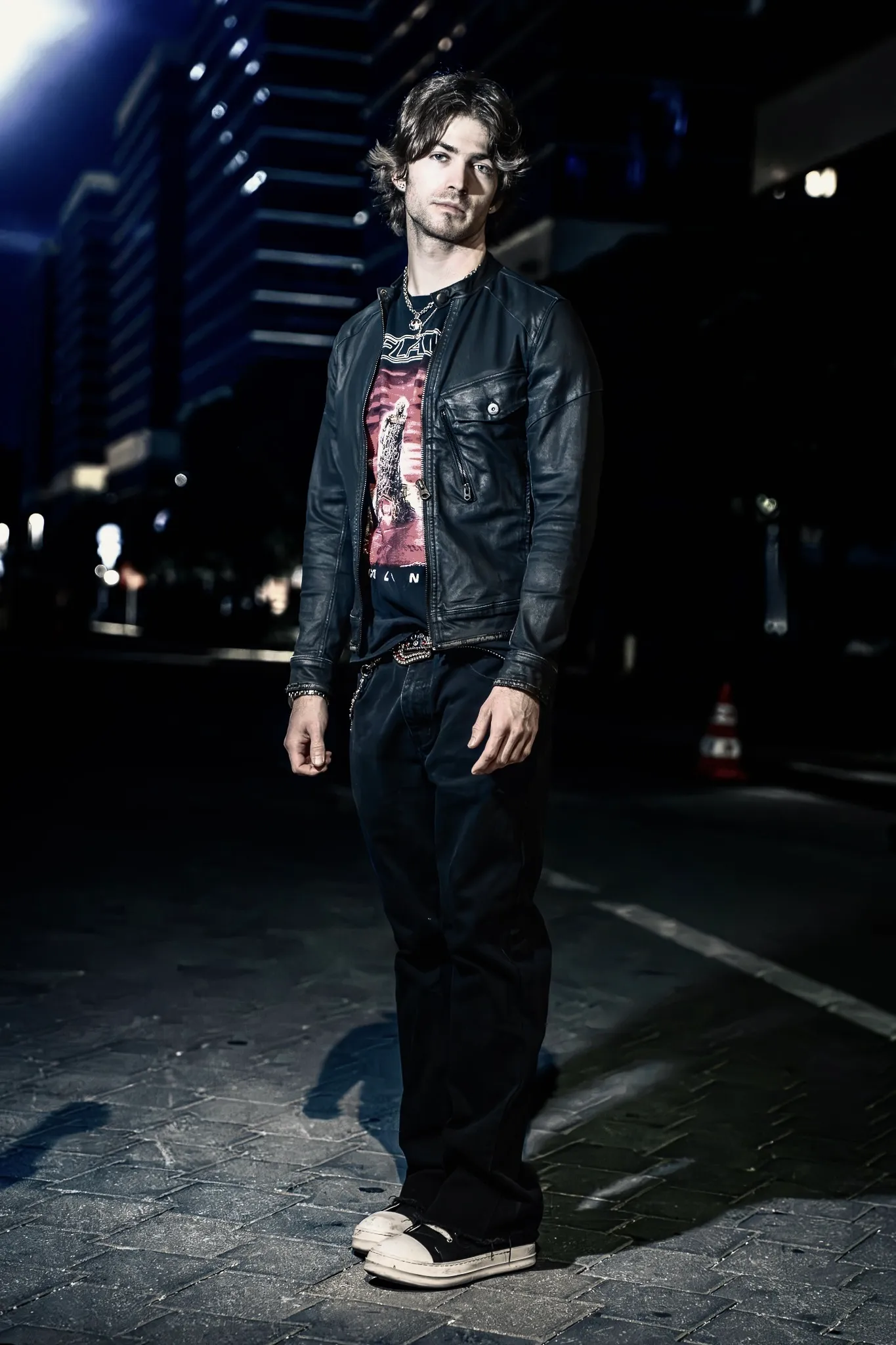 Red Dot in a leather jacket on a city street at night